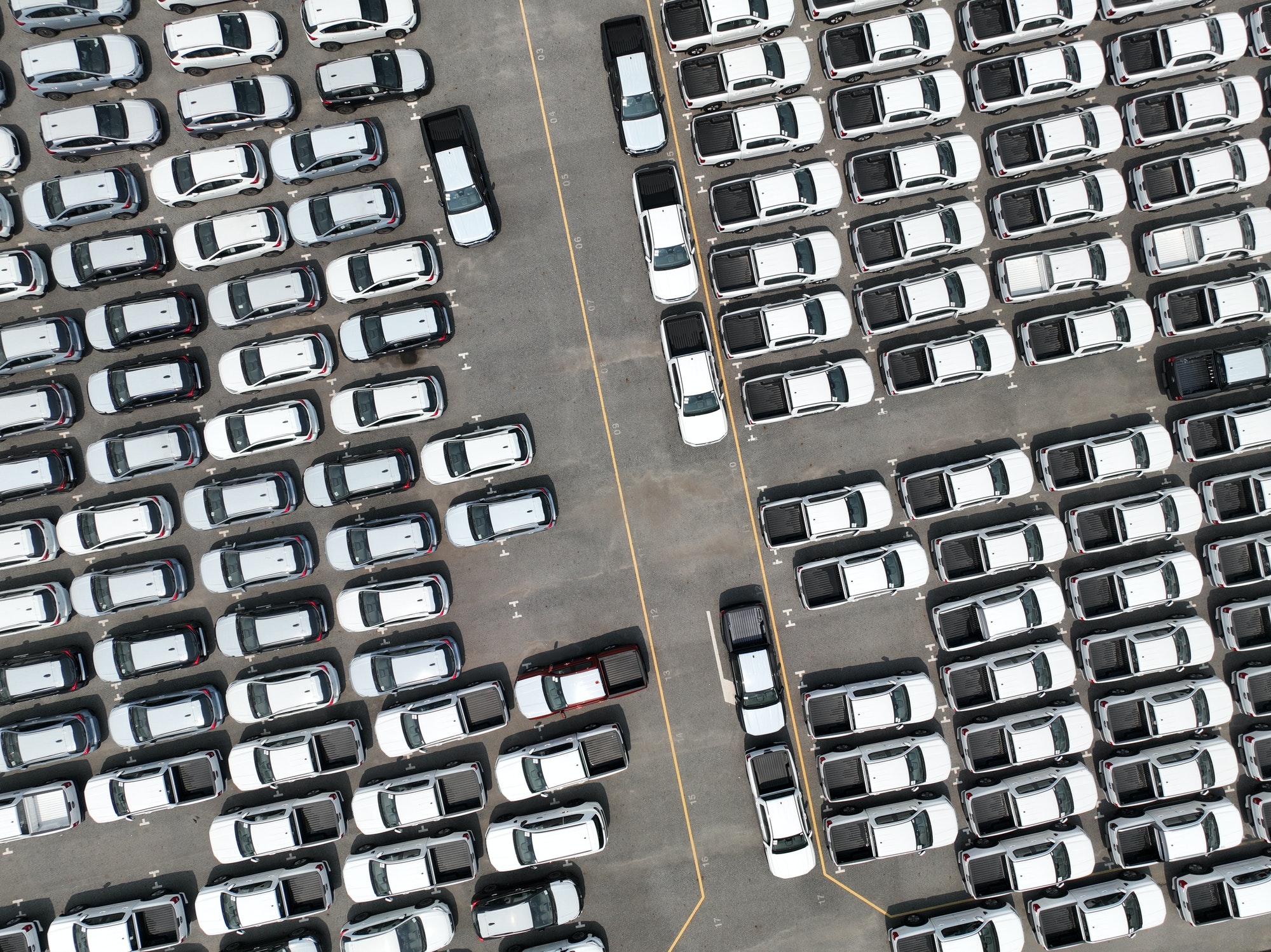 Aerial view of new cars stock at factory parking lot. Above view cars parked. Automotive industry