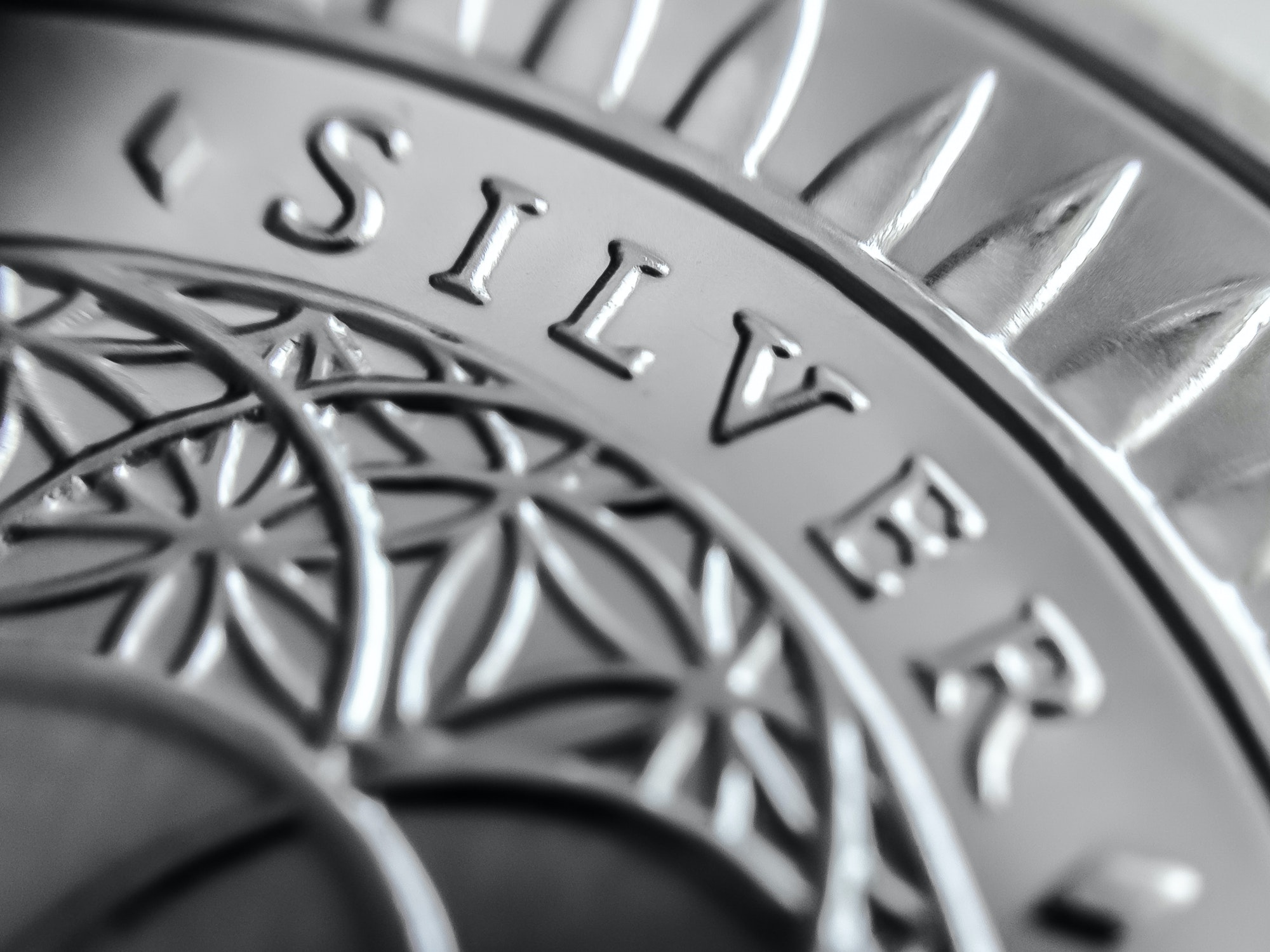 Closeup grayscale of a coin with "Silver" writing