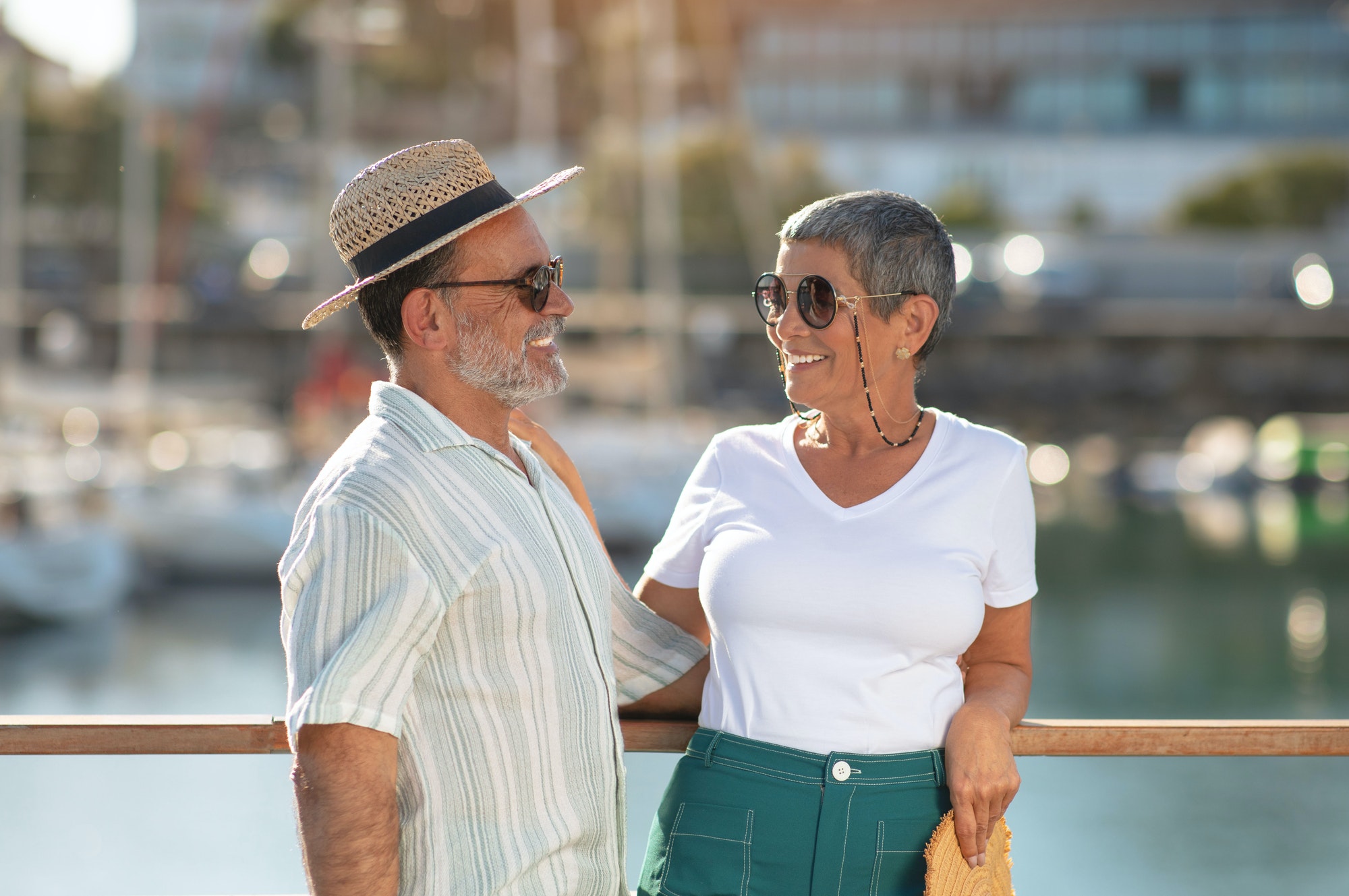 Elderly spouses sharing summer vacation near vessels at dock outside