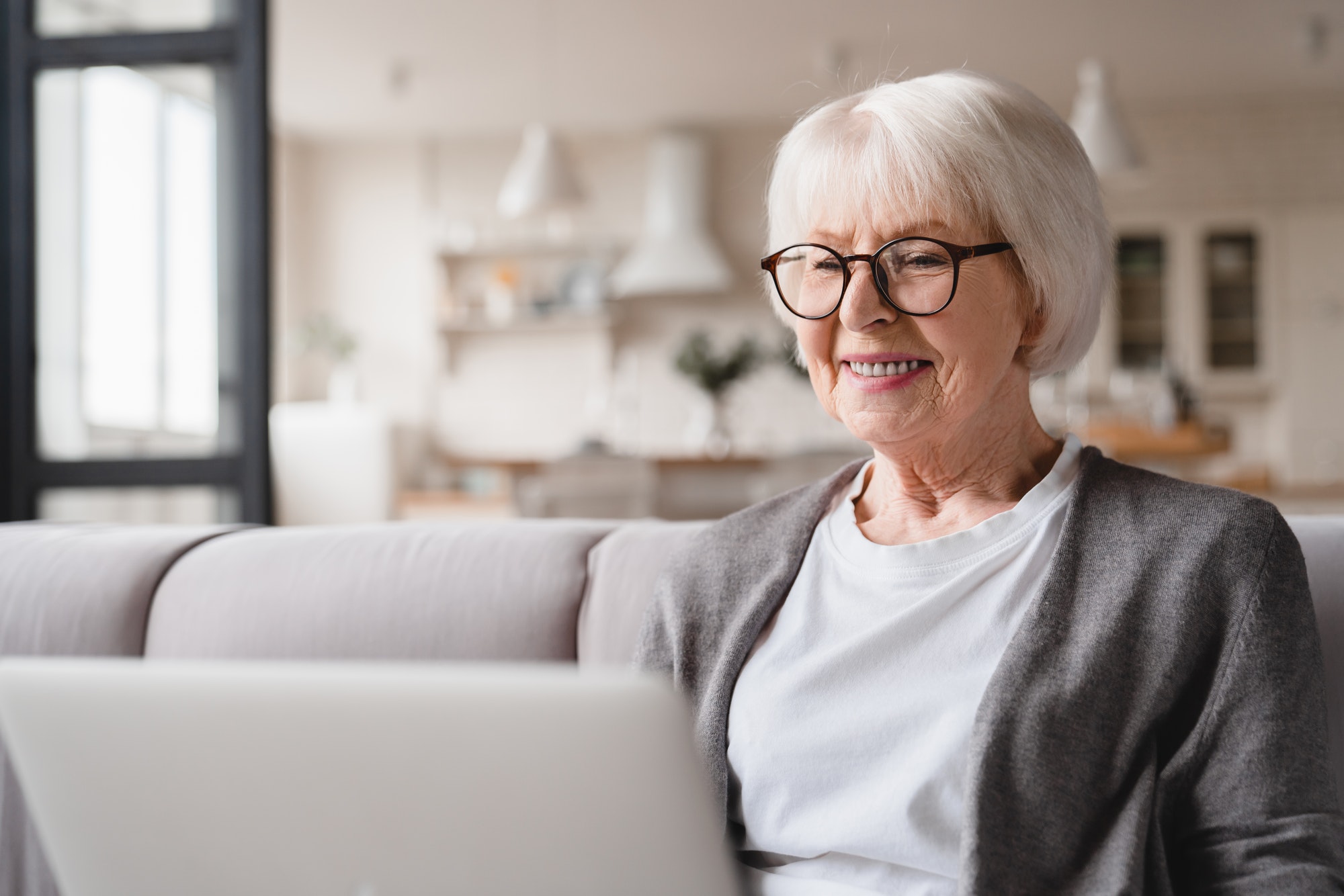 Grandmother using laptop online, working remotely, checking pension, freelance job, watching film